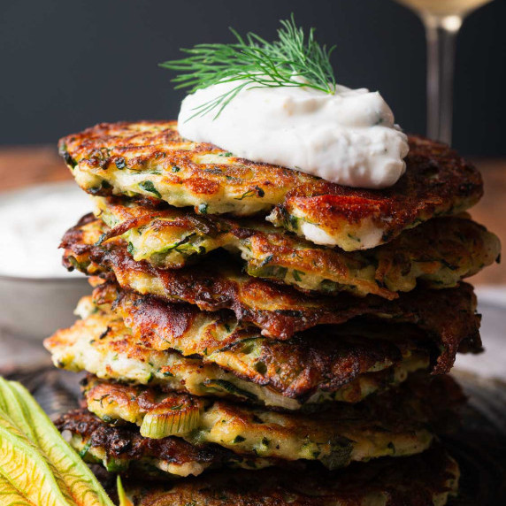 a pile of zucchini feta fritters with garlic yogurt sauce on top