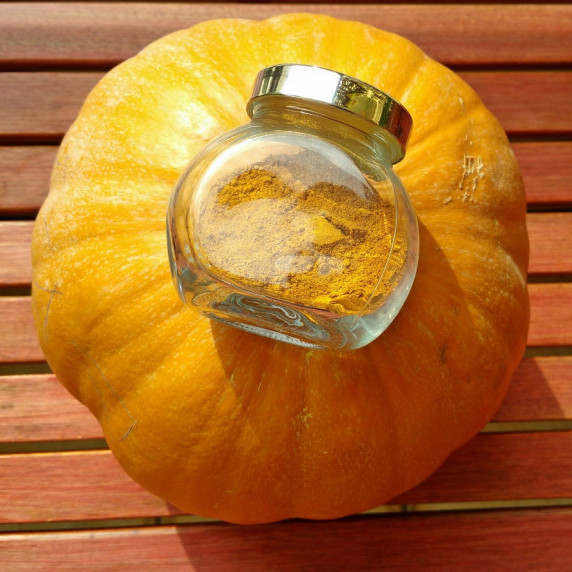 Glass jar of homemade pumpkin spice resting on top of a pumpkin.