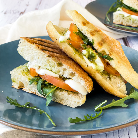 Panini with mozzarella and pesto, on a blue plate.