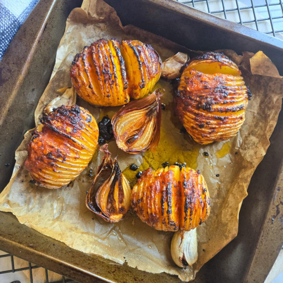 A baking dish of hasselback potatoes brushed with red pesto and a slight char on the thin slices.