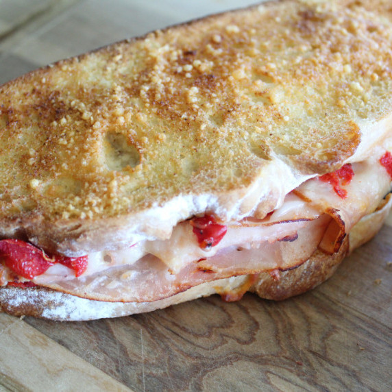 side shot of a roasted red pepper turkey sandwich on a cutting board.