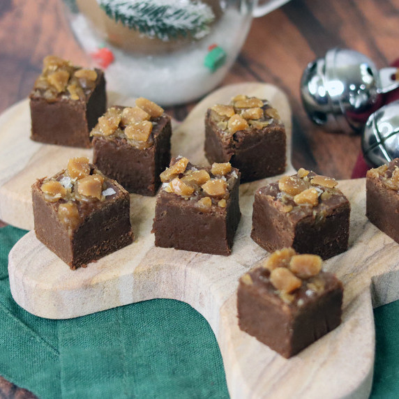 Three pieces of salted caramel toffee fudge arranged on a Christmas plate against a white background