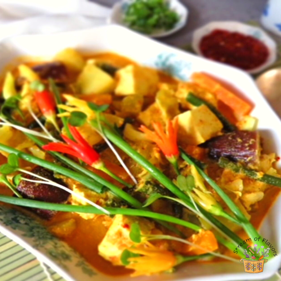 Tofu, vegetables, and chili in a spicy sauce in a white bowl with chili and spring onions