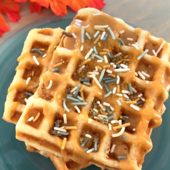 Vegan Pumpkin Spiced Croffles stacked on a blue plate with icing drizzle and sprinkles