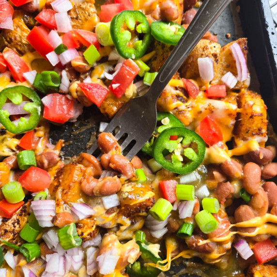 A tray of roasted potatoes along with an assortment of colourful garnishes