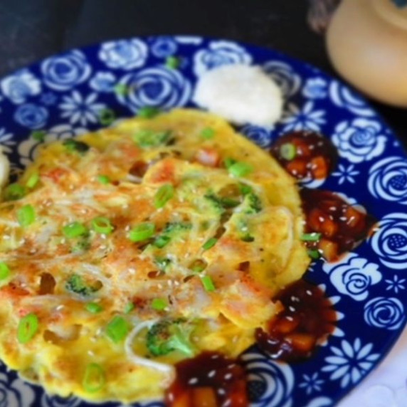 Shrimp Egg Foo Young on a plate with brown sauce and rice on the side.