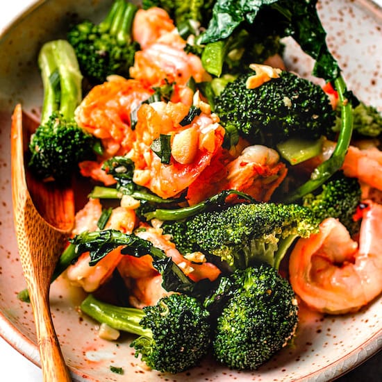Shrimp and broccoli in a bowl with a wooden spoon