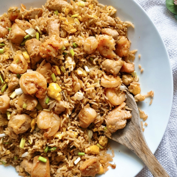 Shrimp and Chicken Fried Rice on a large white plate with a wooden ladle.