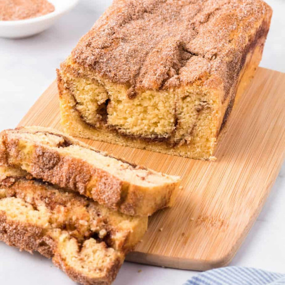 Close up angle of Snickerdoodle bread with several slices cut from the loaf on a cutting board.