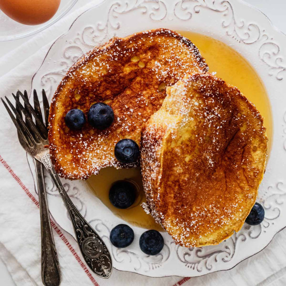 Overhead view of sourdough French toast on a white plate with blueberries and maple syrup