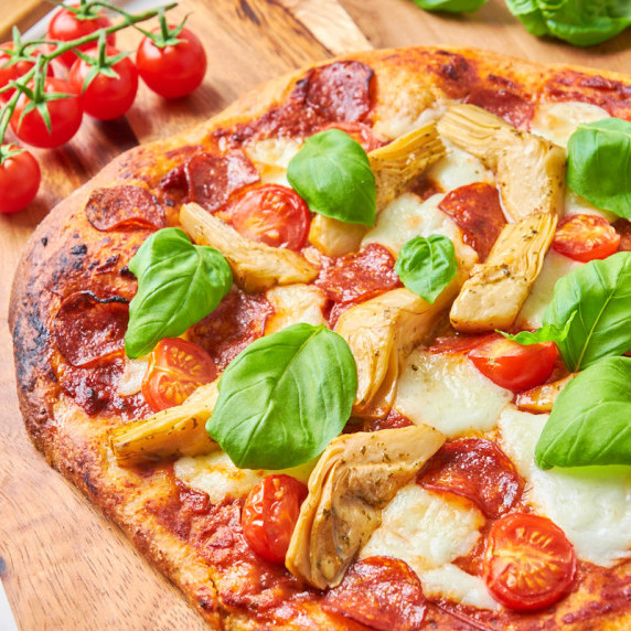 A Sourdough Protein Pizza Crust on a wooden board topped with mozzarella and pepperoni