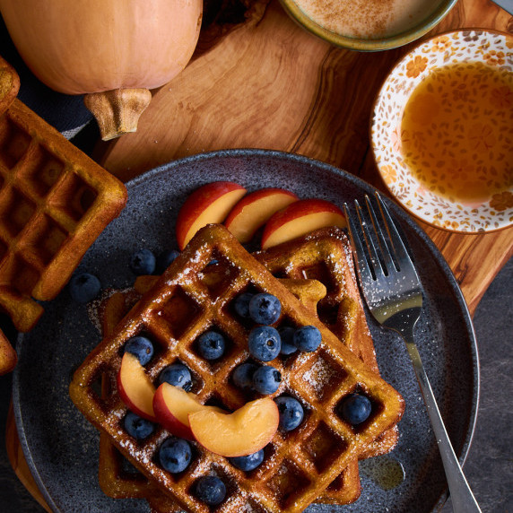 3 Sourdough Pumpkin Waffles with Protein, topped with icing sugar, maple syrup blueberries and plums