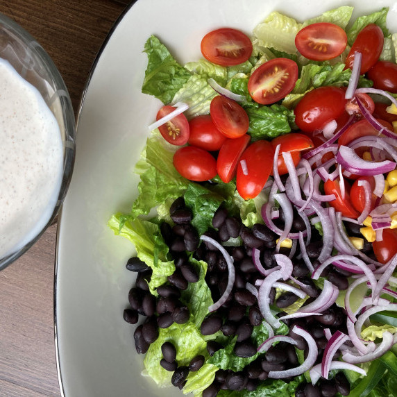 Salad bowl filled with Romaine, black beans, corn, red onion and tomatoes with a creamy dressing.