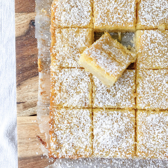 sliced orange spice bars on parchment paper on wooden cutting board on white table cloth