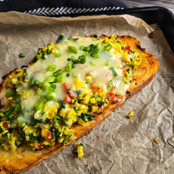 Golden sourdough topped with bright yellow scramble with pops of colourful veggies