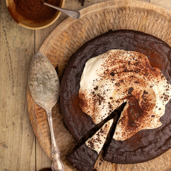 A dark chocolate cake topped with whipped cream, ready to eat
