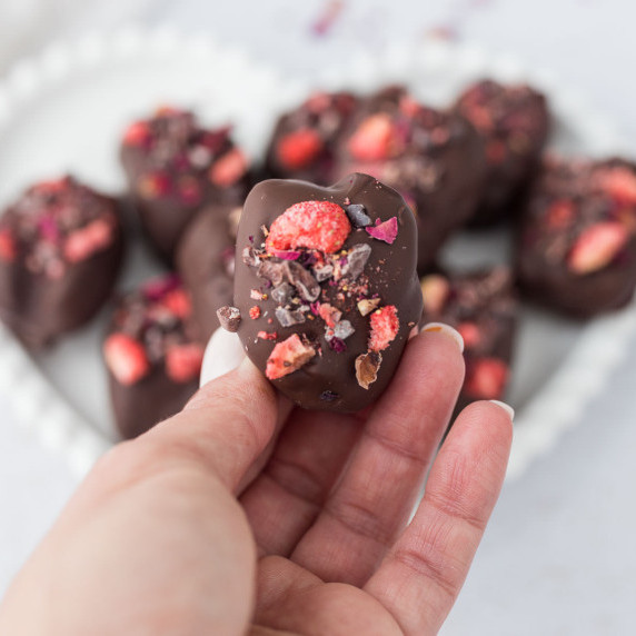 hand holding up a single Strawberry Cheesecake Stuffed Chocolate Covered Dates