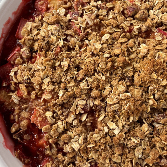 Strawberries and rhubarb with an oatmeal crumb topping in a white baking dish.
