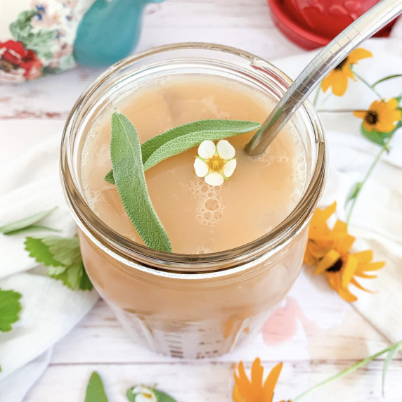 iced strawberry sage green tea latte with sage and a strawberry blossom floating on top