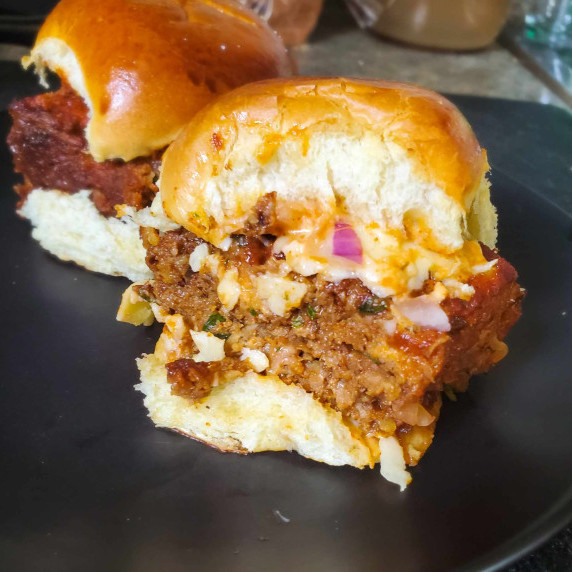 A juicy meatloaf slider on a black surface.