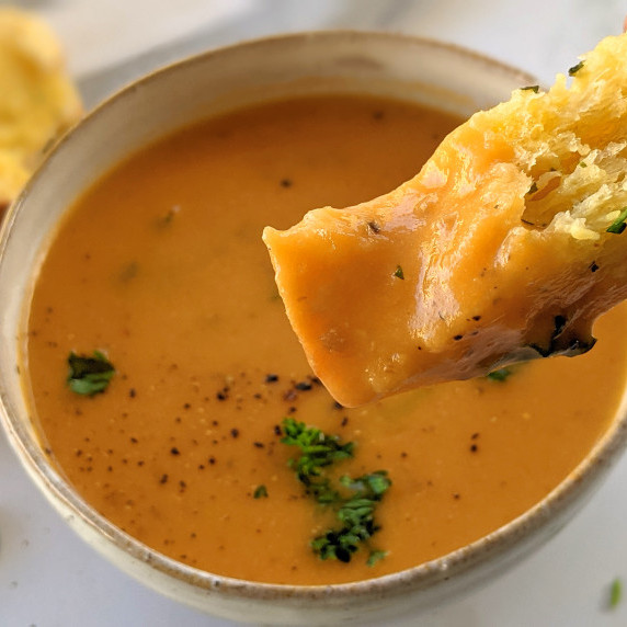 Tomato soup with garlic bread, served in a white bowl 