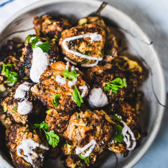 Turkey Zucchini meatballs in a tan bowl drizzled with a sour cream sumac sauce 