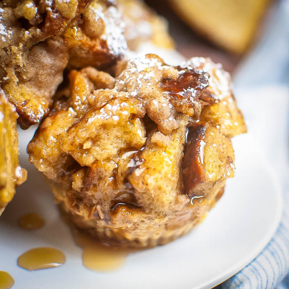 Side close up shot of French toast garnished with powdered sugar and syrup on a white plate.