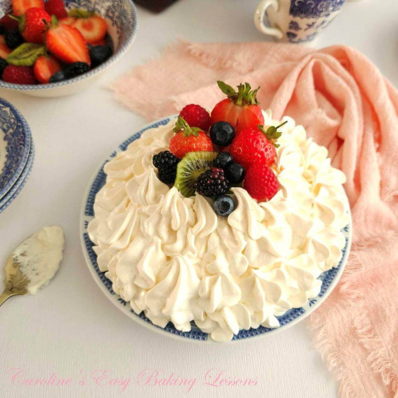 Close angled shot of a Pavlova meringue o plate topped with fresh fruit.
