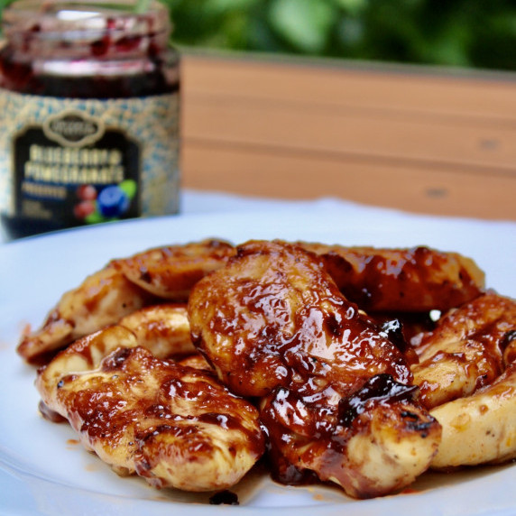 BBQ chicken on a white plate on a tan picnic table.  