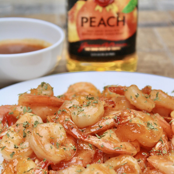 shrimp with dipping sauce on a white plate outdoors on a brown table. 