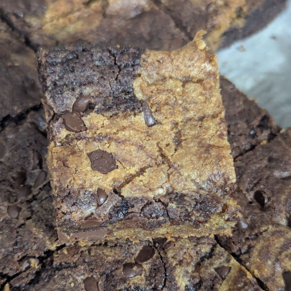 A slice of brownies cookie bars on top of the rest of the pan. 