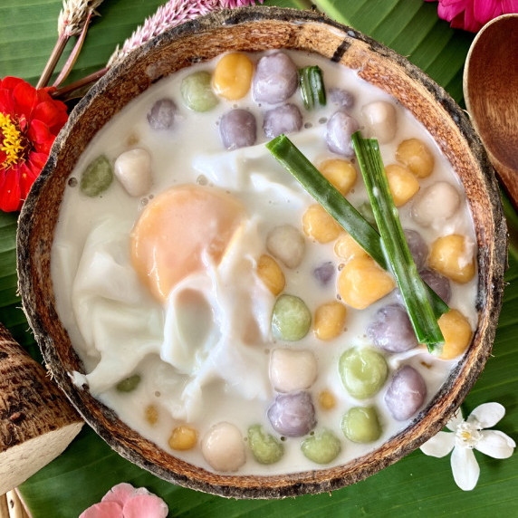 Top-down view of sticky rice balls in coconut milk in a coconut shell.