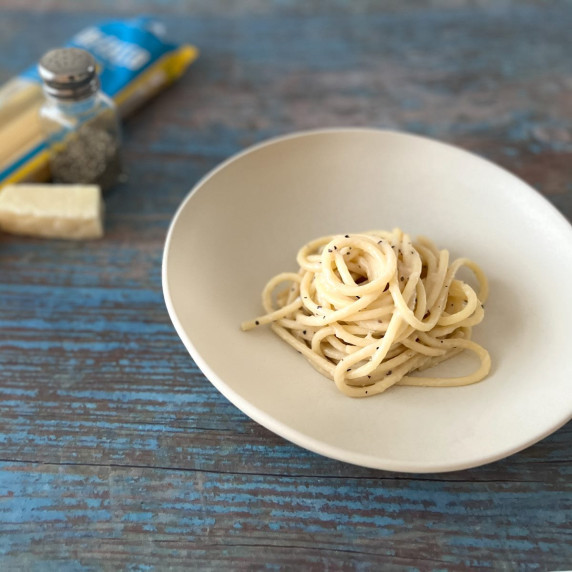 Bucatini cacio e pepe in a white dish on surface