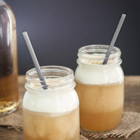 Two glasses of butterbeer on a wood surface.