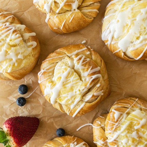 cream cheese danish on parchment paper with vanilla glaze.
