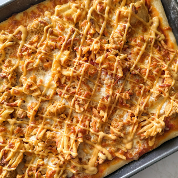 A sheet pan pizza topped with popcorn chicken, waffle fries, and Chick-Fil-A sauce