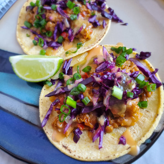 Corn tortillas stuffed with cheesy chipotle lentils, purple cabbage, and green onions.