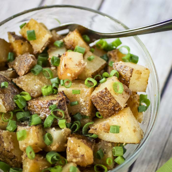 Close up overhead shot of chipotle potatoes in a clear bowl with a fork on the side.