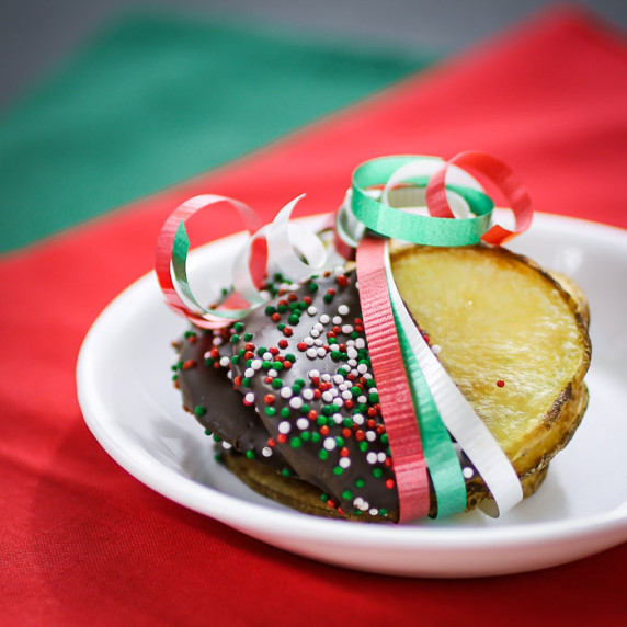Side shot of multiple chocolate covered potato chips wrapped in red, green, and white ribbon.