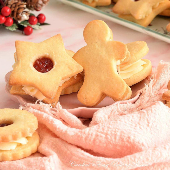 Extra close image of 2 sandwich cookies, in star and gungerbread man shape, with jam buttercream