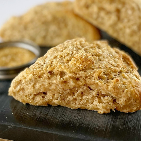 cinnamon scones sitting a black board with a bowl of sugar.