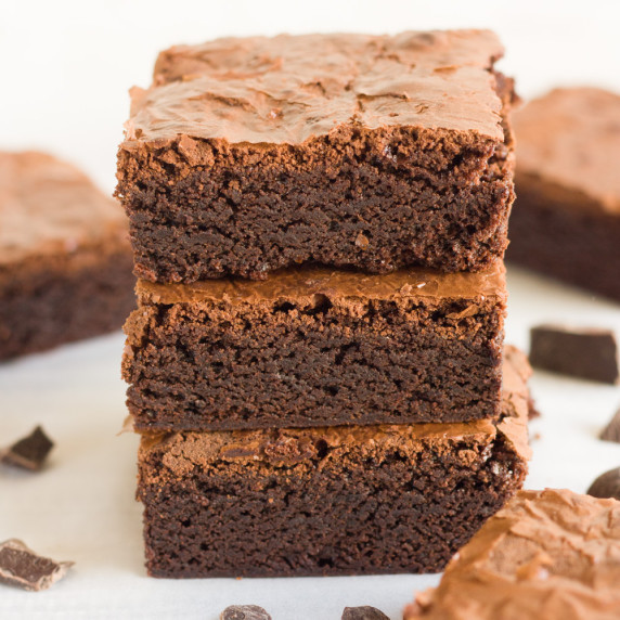 3 brownies one on top of the other surrounded by pieces of chocolate and brownies