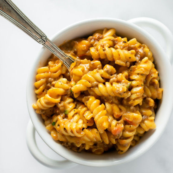 creamy beef pasta in a white bowl with a fork.