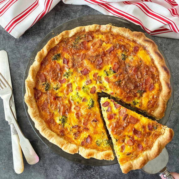 Lifting a slice from a broccoli and bacon quiche.
