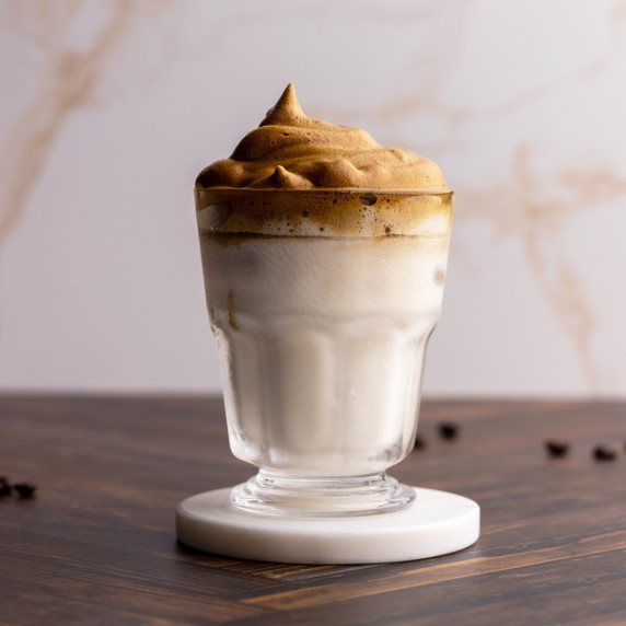 Dalgona latte on marble coaster head on shot.