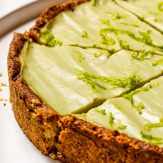 A sliced vegan key lime pie on a white plate.