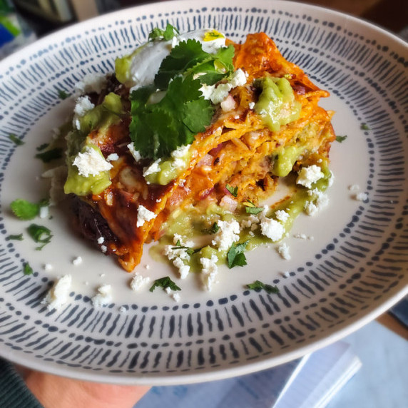 Layers of golden tortillas, green sauce / herbs, and crumbly white feta.