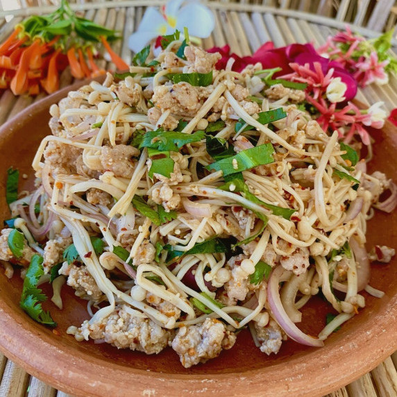 Enoki mushroom larb salad in a clay dish.