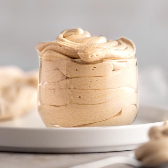 Espresso buttercream in a small glass jar, on a white round plate.