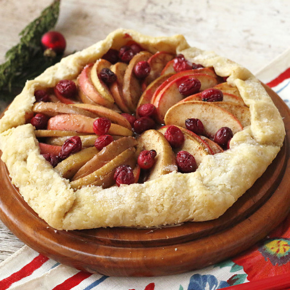 An apple cranberry galette on a round wooden board.